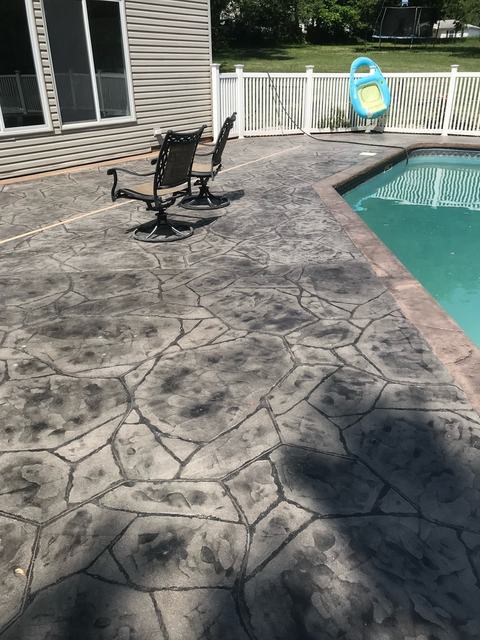 Stamped concrete pool deck with patio chairs at a Florida home